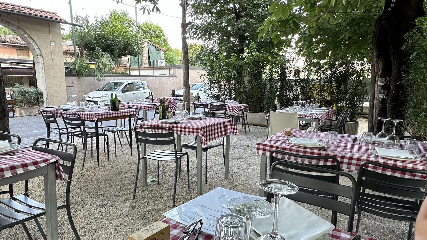 Sala interna della Trattoria Antico Sole con travi a vista, tavoli in legno e camino acceso
